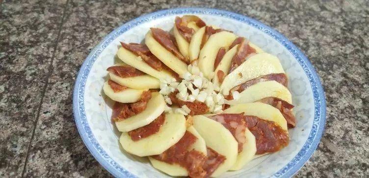 一片土豆压一片腊肠, 蒸一蒸, 撒上料汁, 入口即化