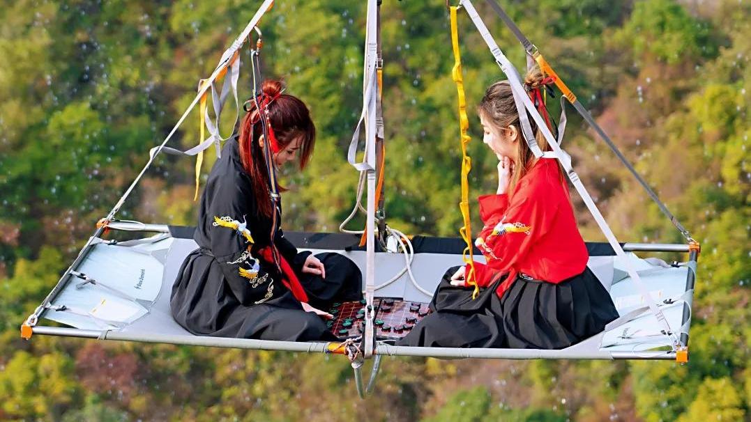 胆颤心惊！两美女竟然在悬空数百米的高空吊床上下象棋。