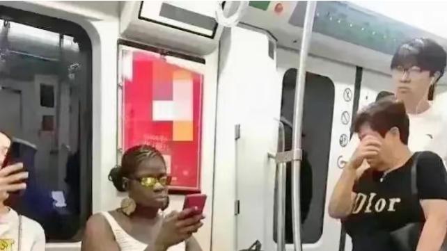 一位黑人女士在地铁上占据了三个座位，一位阿姨礼貌地提醒她让座
