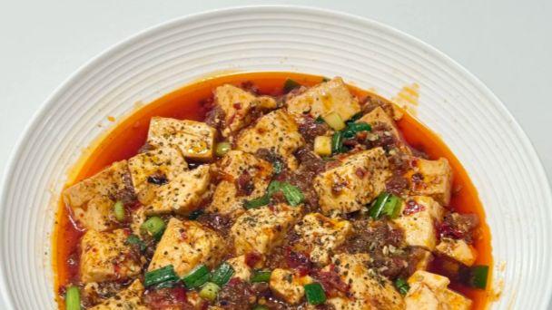 嫩豆腐裹满红亮汤汁，麻与辣在舌尖绽放