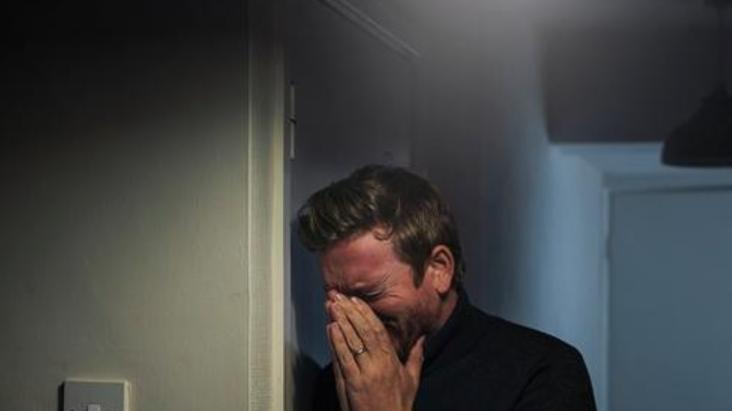 寒冬深夜，客厅只亮着一盏小灯，男人蜷缩在沙发上，​手里攥着皱巴巴的账单无声流泪。