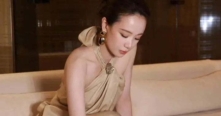 李梦这一袭香槟金缎面裙，优雅躺出来，挂脖款露肩颈是重点。