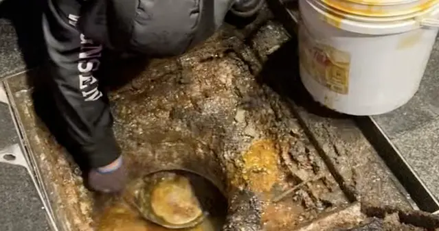 黑衣男子凌晨在湖南长沙闹市区打捞地沟油，身旁停着一辆印有“丹鸟快递”字...