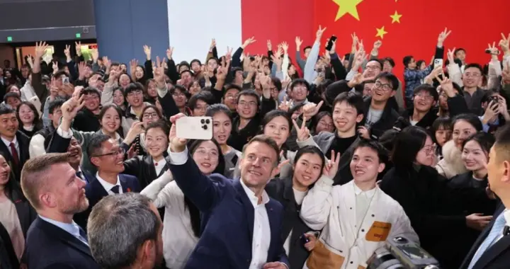 马克龙单手举起手机自拍，献花女生站其身后抢镜，清纯五官美翻了