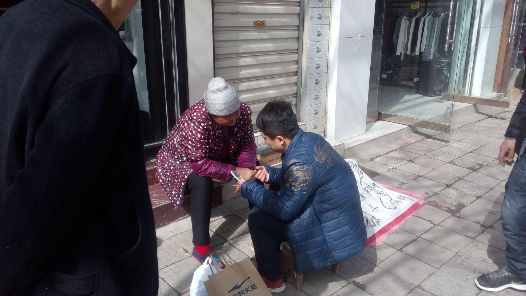 六旬老太街头取脸上黑点, 一分钟取一个