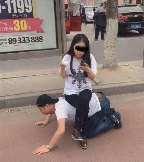 男子跪地给女友当凳子, 女友却坐着玩手机吃冰糕!