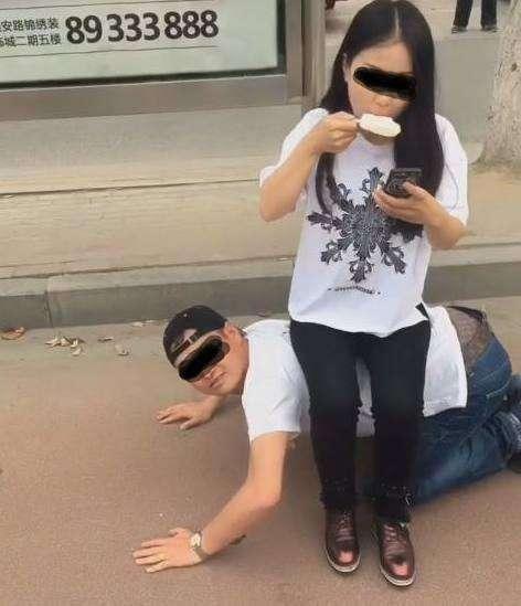 男子跪地给女友当凳子, 女友却坐着玩手机吃冰糕!