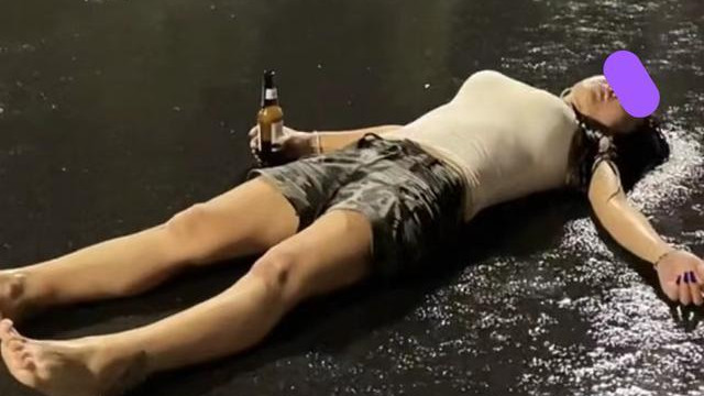 |一女子光着脚丫走在马路上，手上还抓着一瓶啤酒