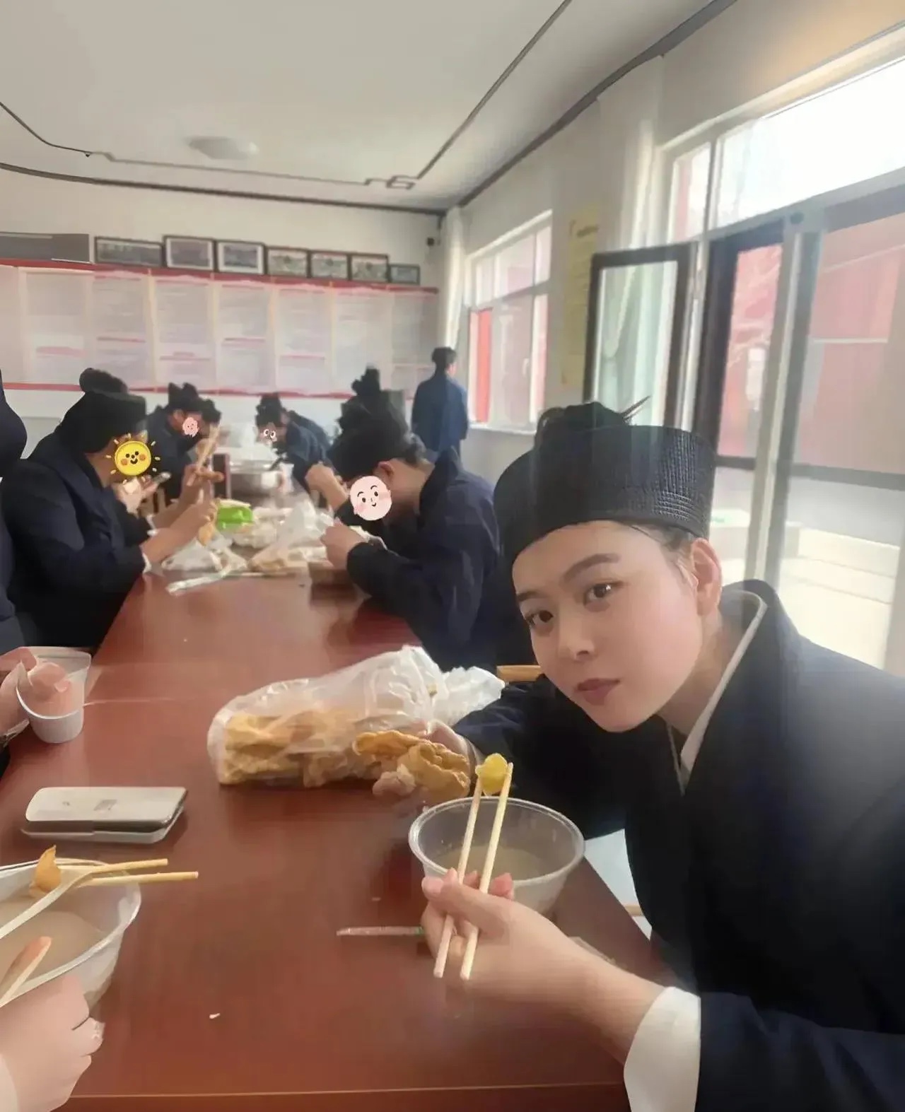 道观里，一位道姑坐在长凳上，吃着煎饼，喝着红薯粥。这一幕被游客拍了下来。面对镜头