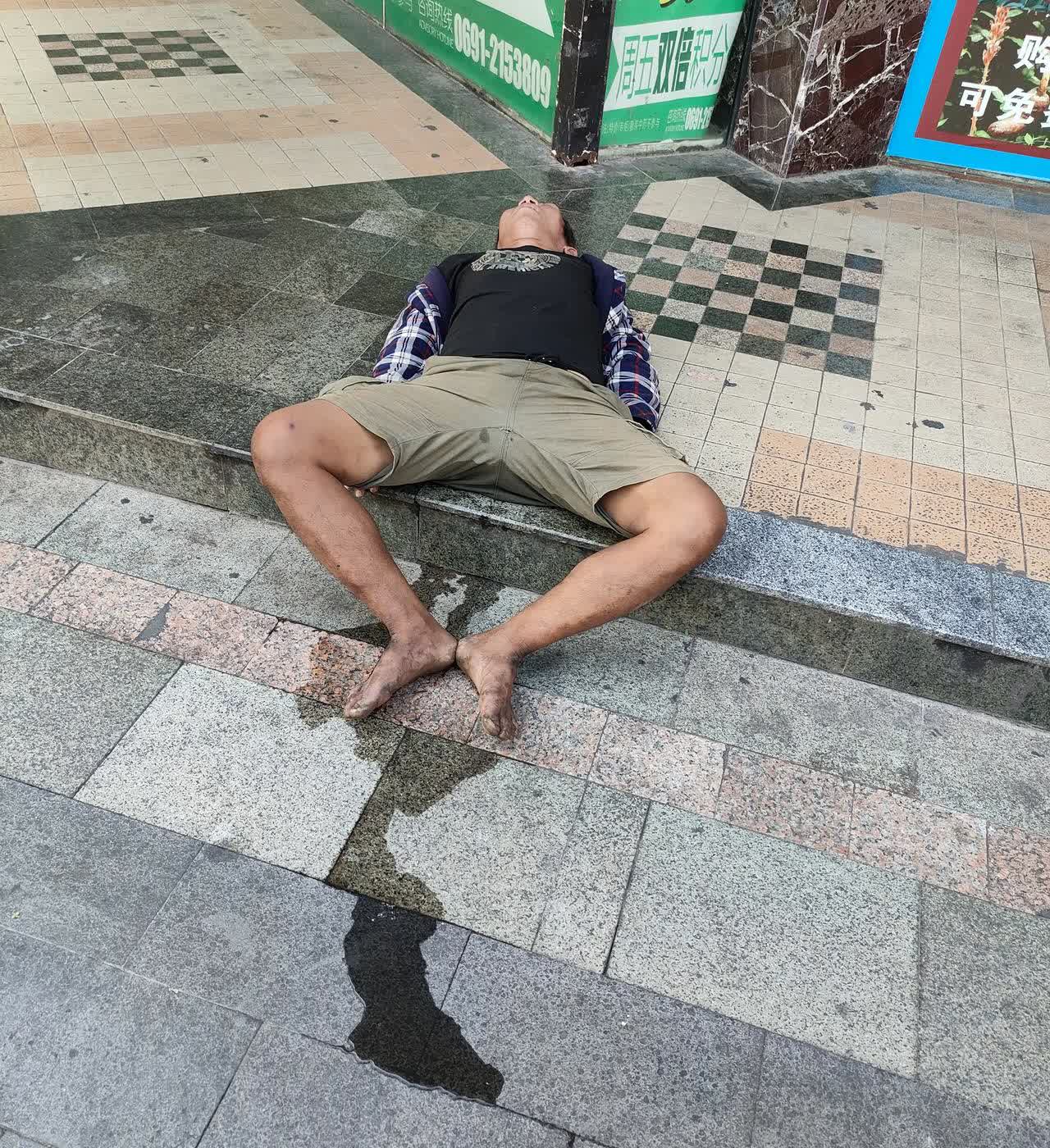 在西双版纳的街角，我看到了一个令人纠心的场景。阳光明媚，道旁树木苍翠，人们幸福快