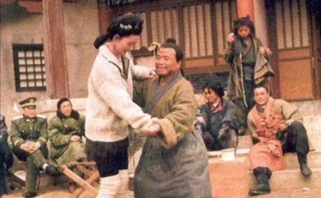 1998年电视剧《水浒》拍摄现场，“潘金莲”和“武大郎”的扮演者在剧组人员的围观