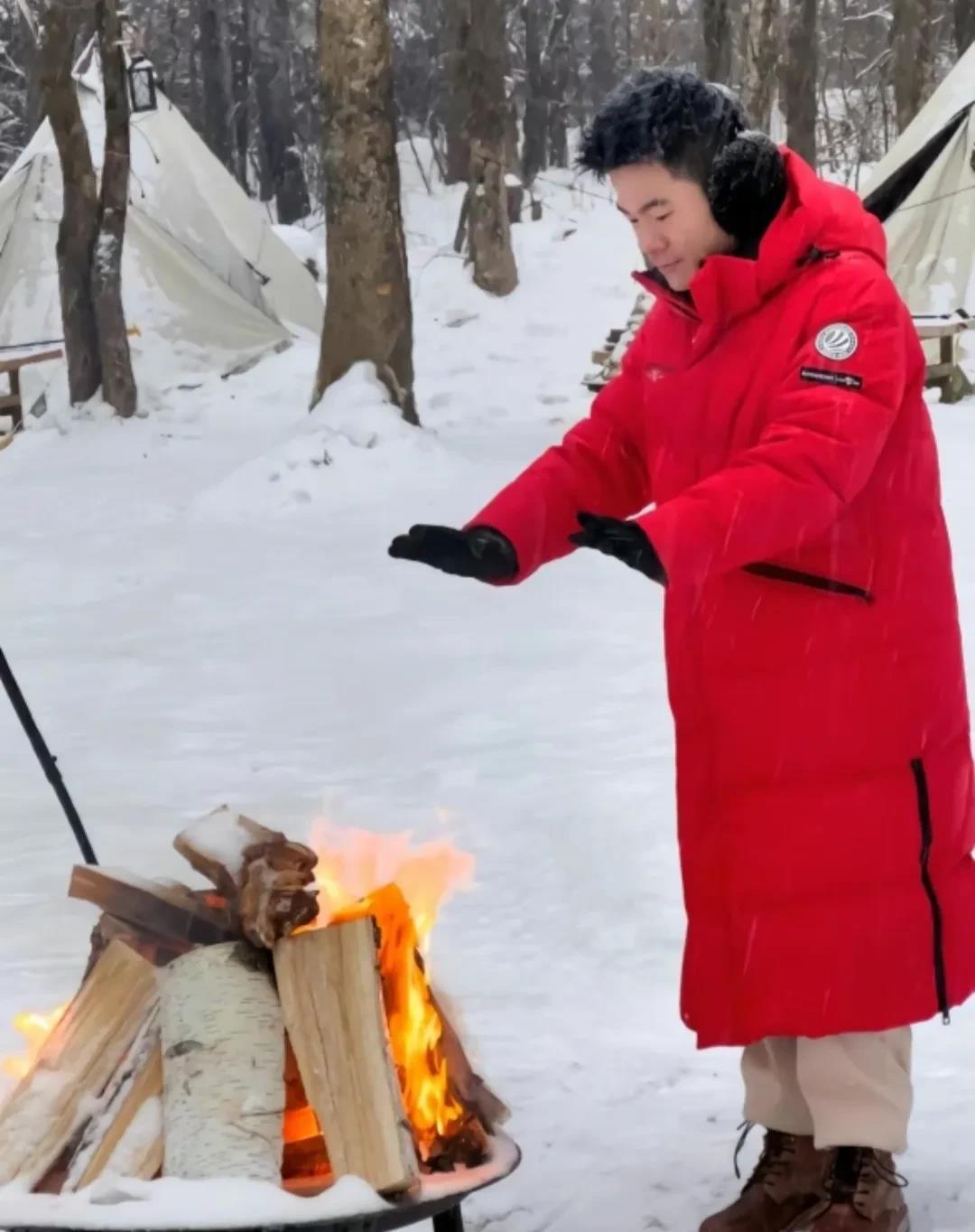 
宇辉身穿红色羽绒服，在雪地烤火，表情忧郁、面对镜头才强颜欢笑。与其委屈自己，不