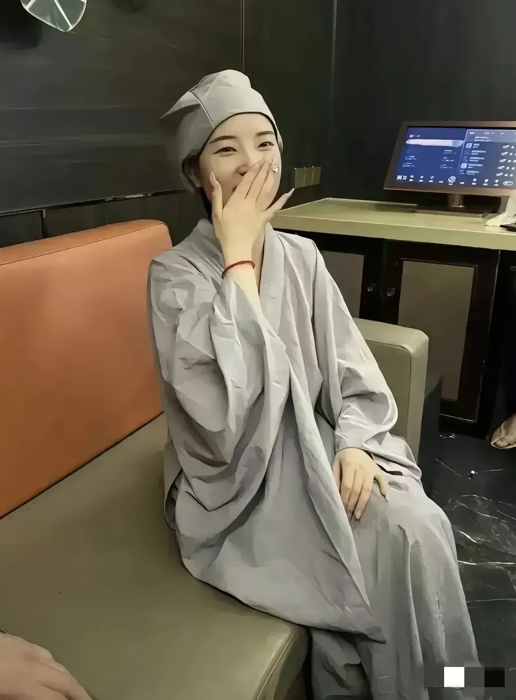 一位容貌秀美的小道姑，虽已出家，却散发着独特的魅力。她的微笑轻轻掩嘴，玉一般的手