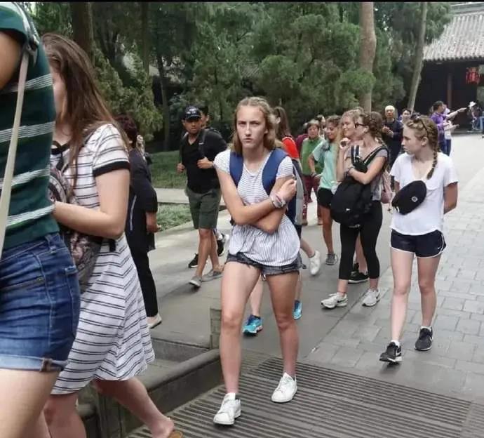 在中国的一个旅游景点发生了以下一幕：一个中国男子拿起手机对着刚刚进入景区大门的外