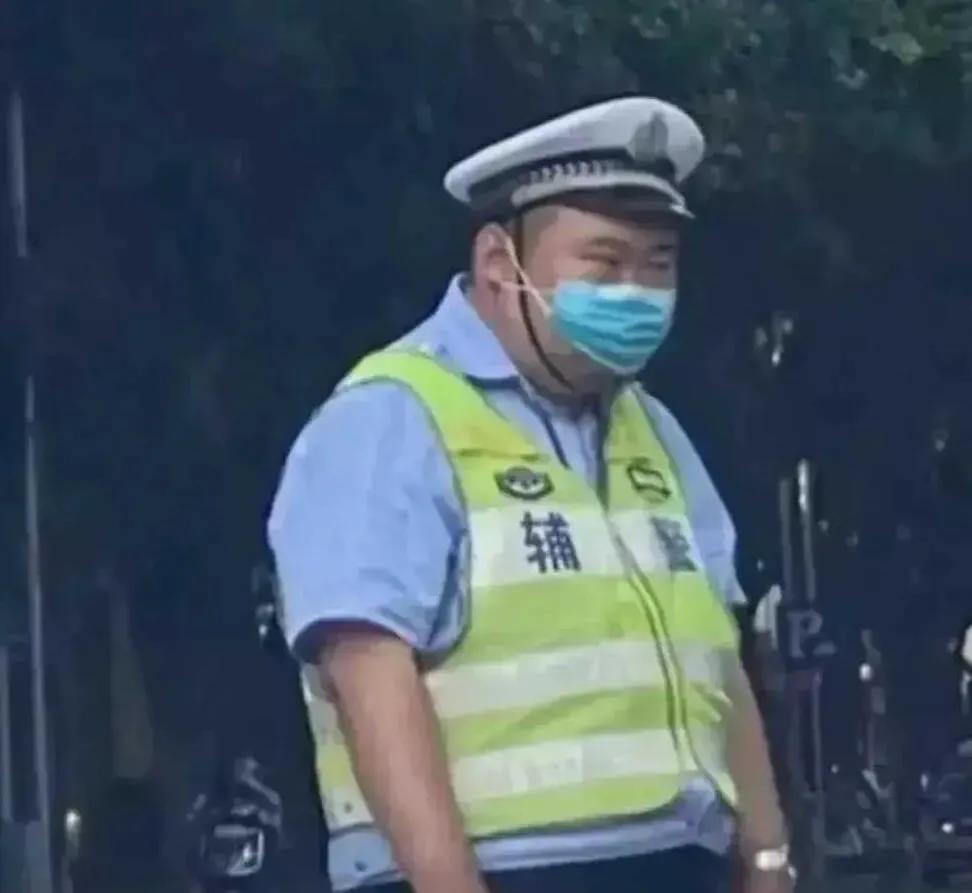 他穿着警服，站在街头，好像是在教育驾驶员。但是他是辅警，不是正式警察。每天在人行