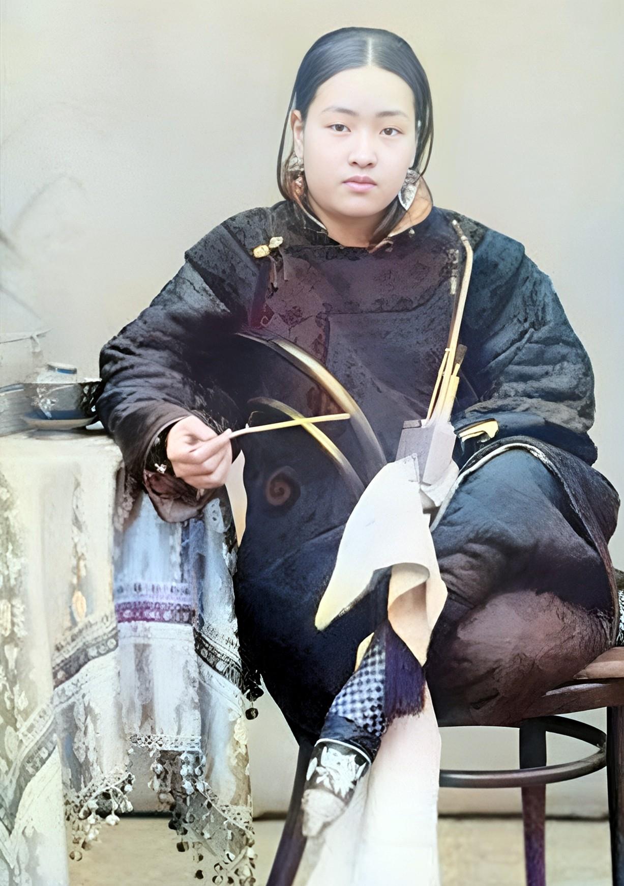 在晚清时期，一位相貌端庄、体态丰腴的女子坐在家中拍摄照片。她的美貌超越了当时的大