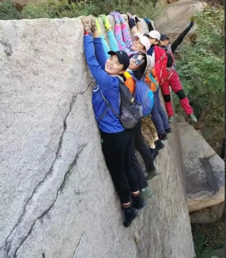 这群大妈在郊外旅游时，抓住了岩石的边缘，并摆出了令人惊叹的高难度动作。
大妈们紧