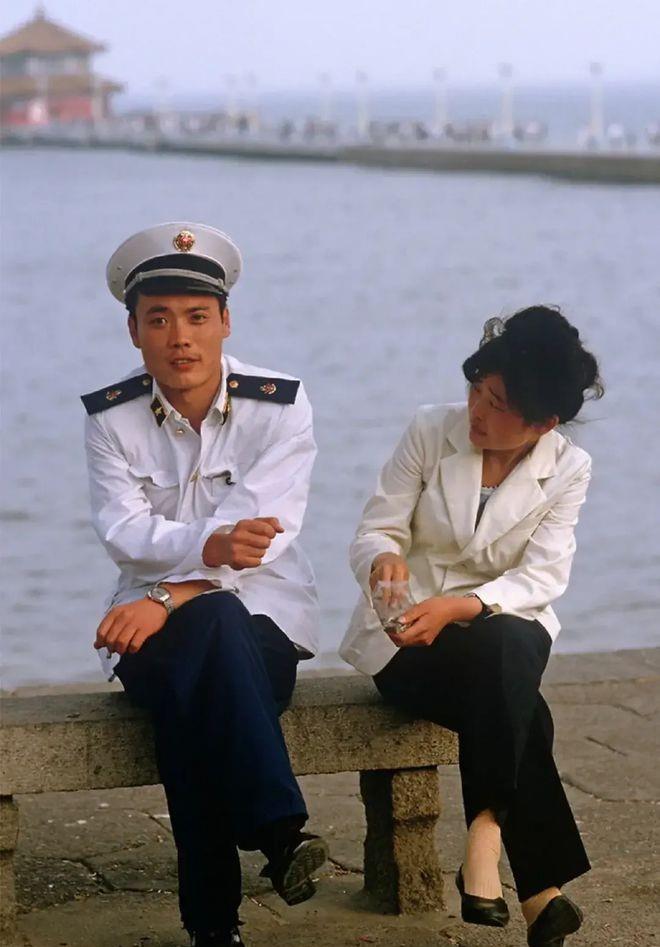 这幅照片拍摄于1985年，在青岛海水浴场附近。一对情侣静静地坐在石凳上交谈着。那