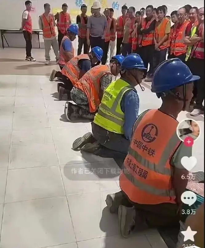 这个小伙子的拍照角度属实挺清奇！

一群人围着一排跪下的工人，不知道的还以为哪里