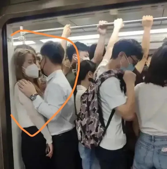 车厢里人山人海，我站在游泳池一样的地铁里感到十分尴尬。对面站着一个穿着白衬衫和黑
