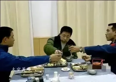 在升空之前，杨利伟身着军大衣，与两位战友举杯共饮。那顿简单的饭菜，用的还是普通的