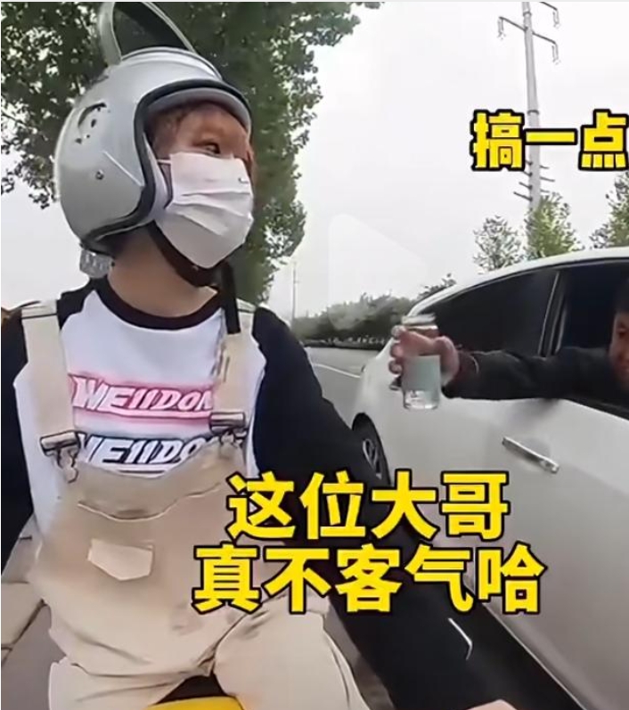 头一次见到这么“高级”的头盔。女子戴水壶头盔等红绿灯，旁边大哥居然递水杯要水。网