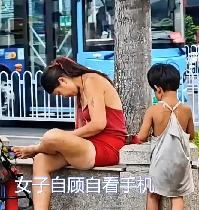 在厦门杏林看到一个流浪的女子，穿着睡衣玩手机，旁边的孩子在一边安静的玩着。 女子