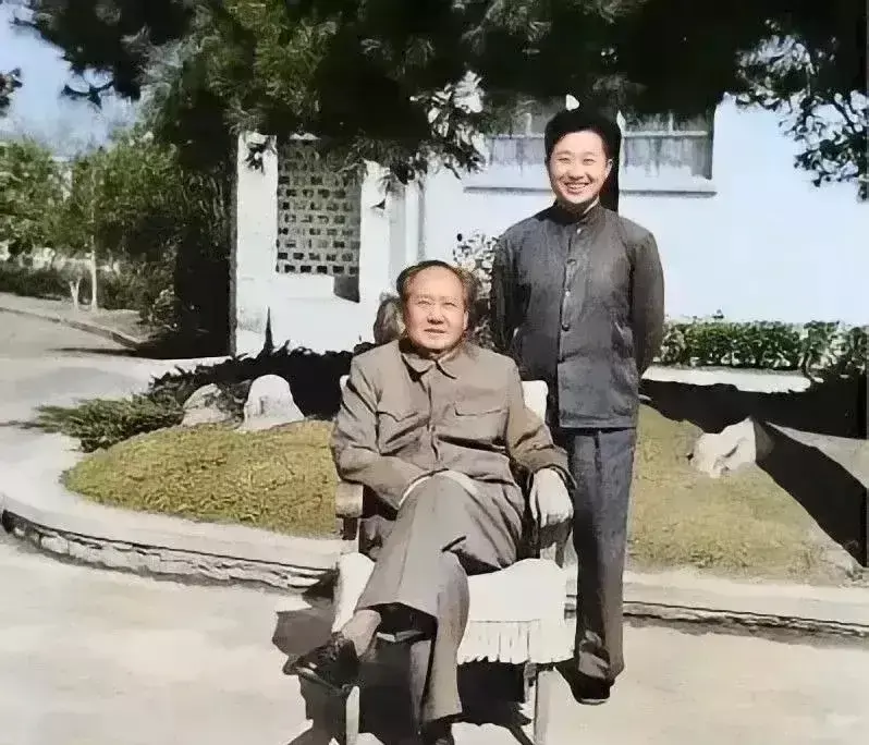 这是一张难得一见的生活照，老人家坐在院子里晒太阳，脸上带着笑容写满慈祥，站在他身