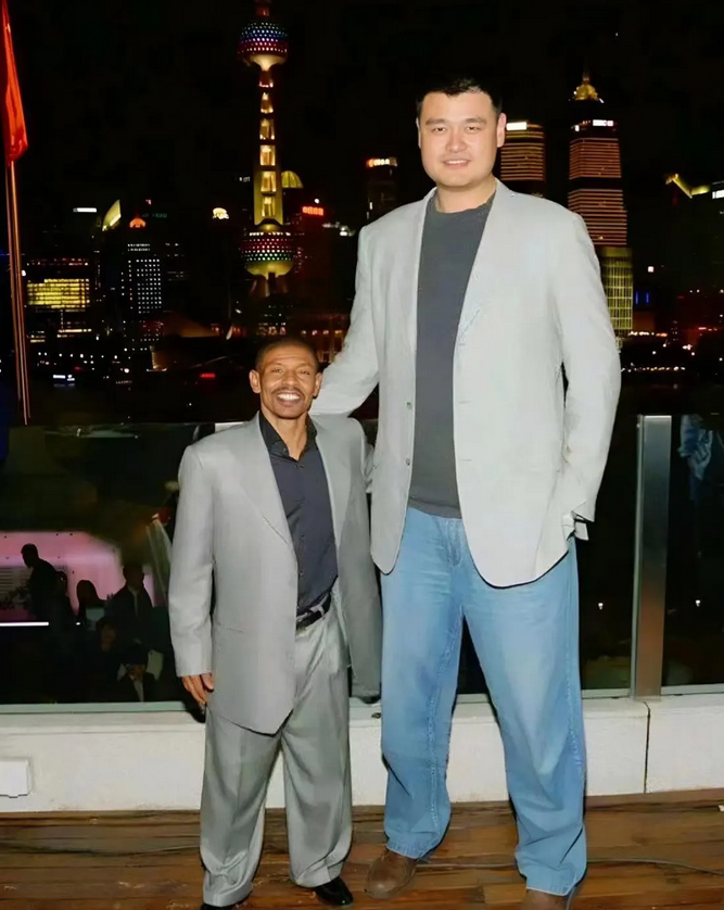 跟姚明在东方明珠前合影的这个矮个子，貌似有点猥琐，尤其是他的那身穿戴。

这张照