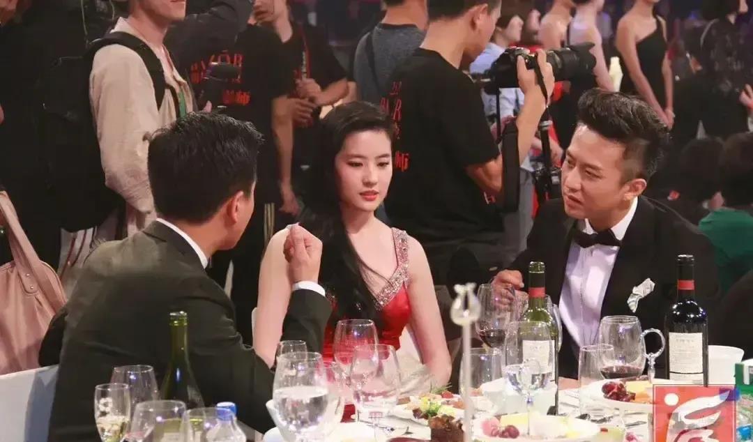 两个男人如此近距离地凝视着刘亦菲，他们努力保持着外表的得体，但内心可能早已躁动不