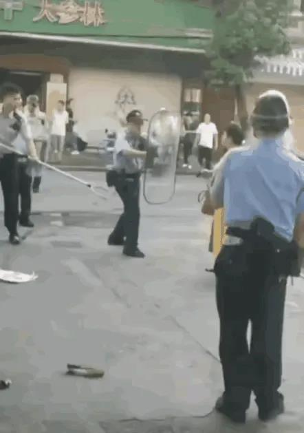 在湖南的一条街头，一名中年妇女手持两把菜刀与十几名全副武装的警察发生了对峙。警察