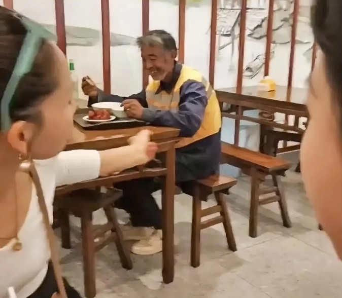 
饭店里，一位白发环卫工老人正在吃饭，邻桌一名女子看了看老人吃的东西，一个举动让