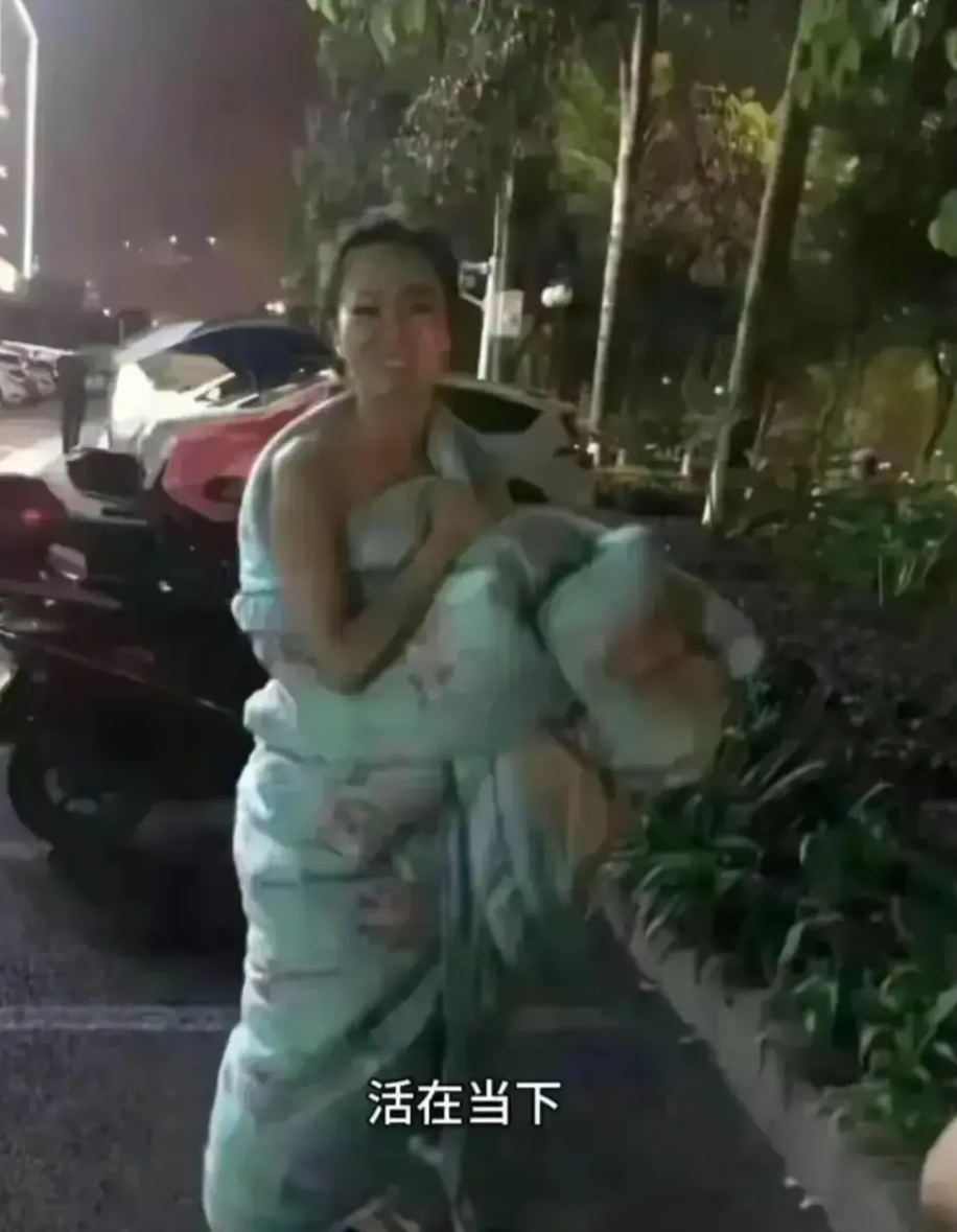 甘肃地震下的一幕。一女子地震后裹着被子就逃了出来，安全之后她露出了笑容。