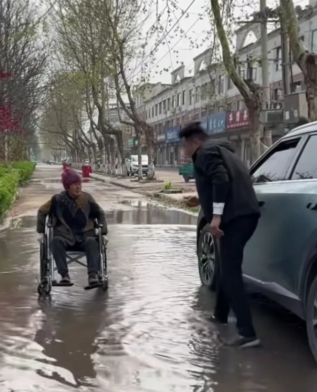 下班的路上，雨水把路面淹没了，有位老奶奶自己推着轮椅，进退两难，这时，车上有一位