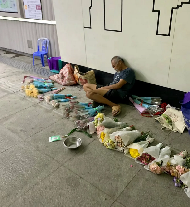 深圳一地铁通道内，一女子看到卖花的老爷爷累的睡着了，就想把花买下让老人能回家好好