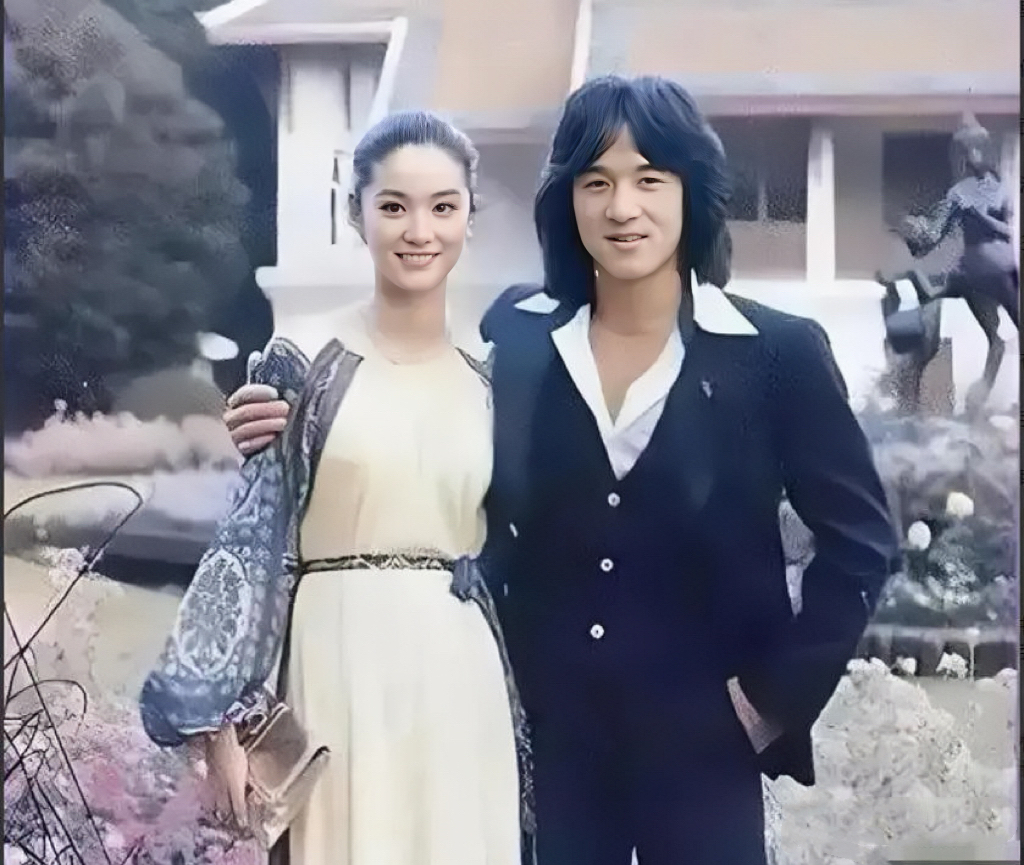 年轻时的林青霞与成龙，男帅女靓。镜头下，成龙留着长发，穿着西装，左手插兜，右手揽