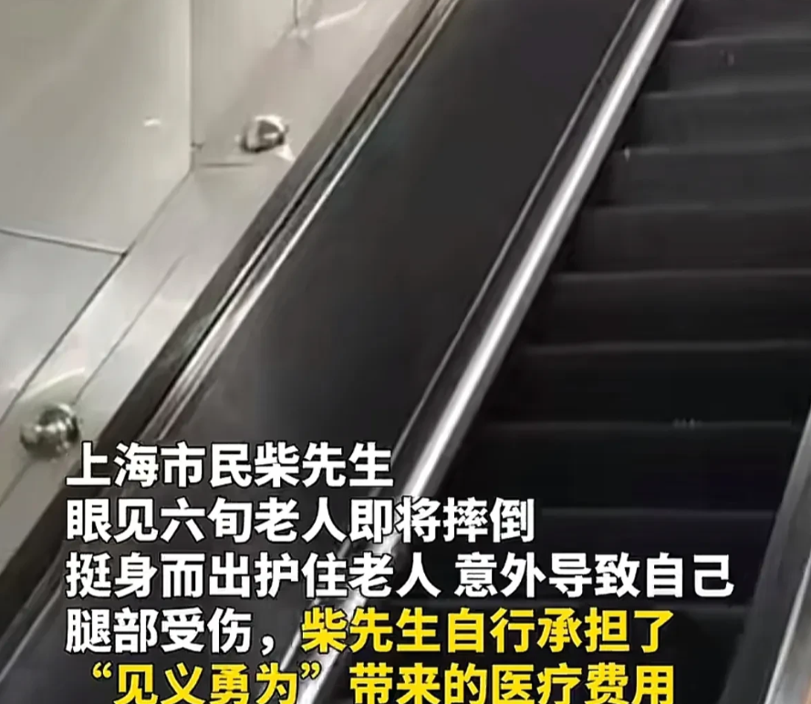 上海，一老太乘坐地铁站的自动扶梯时，突然站立不稳向后摔倒，后方一男子急忙上前，护