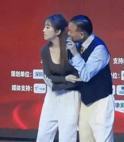 万梓良在商演中强行搂抱伴舞美女，美女一脸嫌弃，一直在抗拒，这算不算公开性骚扰？