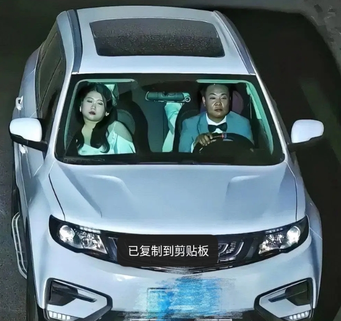 夜色中，迎面驶来一辆银色的小轿车里面一男一女并肩坐在车内，女的靠着睡着了，男的专