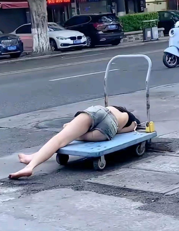 这个美女咋滴咯？酒喝多了喝醉了？为哈子倒在板车上一动不动睡戳了？这是鞋子都不见了