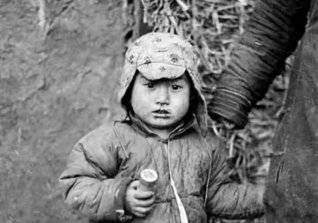1937年4月15日，5岁的小金子目睹了父亲死在日军的刀下后，伸出满是伤痕的手，