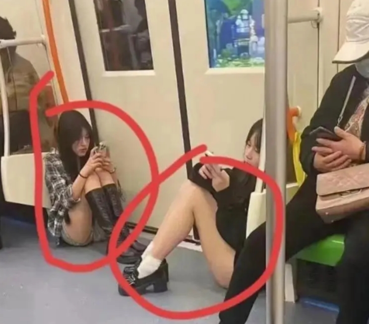 在地铁的一隅，两位青春洋溢的女孩坐在地上，手机屏幕映照着她们专注的神情。没有座位