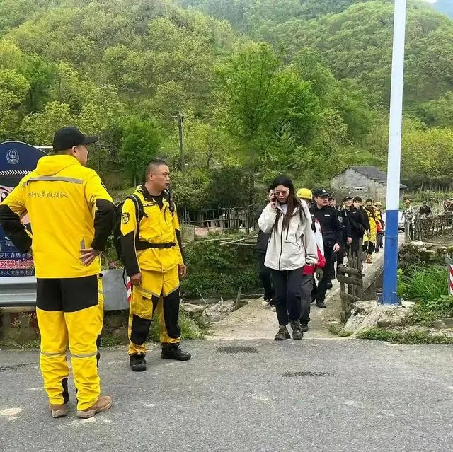 仔细看救援队员们打量这个女子的眼神，在右前方两个穿金色服装的队员看向她时，眼神里