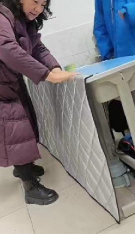 天气寒冷，班主任罗老师注意到靠门第一排的学生因同学进出会受冻，自费准备了一条挡风