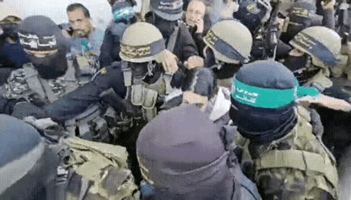 在第三批释放人质的过程中，一群戴着面罩的哈马斯武装分子把一名以色列女兵夹在中间就