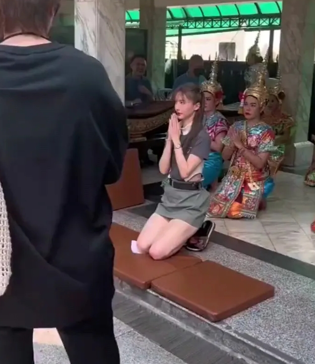 金晨在泰国的寺庙里身着超短裙，虔诚地跪地拜佛，脸上洋溢着灿烂的笑容，看起来心情十