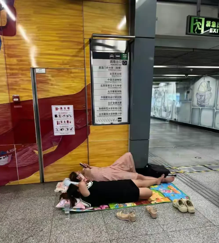 太闹心了！在一个地铁站内，两名女子为了省空调费，直接带着垫子跟枕头，来到了地铁站