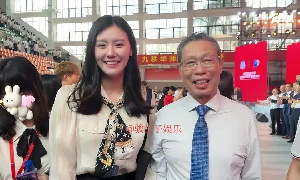 游泳金牌得主刘湘回到母校，并与钟老合影留念。她的着装十分恰当，一件白色衬衫搭配黑