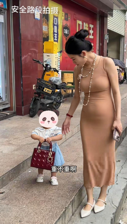 女人从小就喜欢包包，这么小的孩子喜欢包包，一直拿着不给妈妈