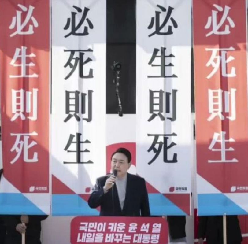 此刻的尹锡悦就像一位京剧演员，而且还是白脸丑角，身后插满了各种flag。

当初